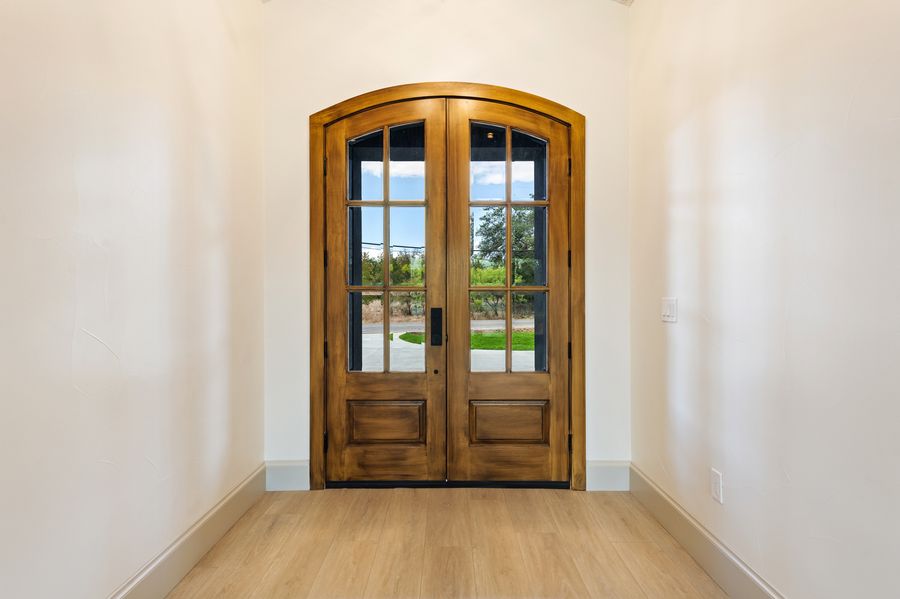 Arched wooden double entry doors with glass panels