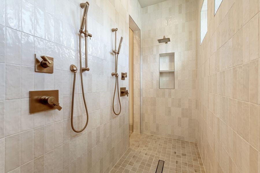 Shower with vertical cream tile and brass fixtures