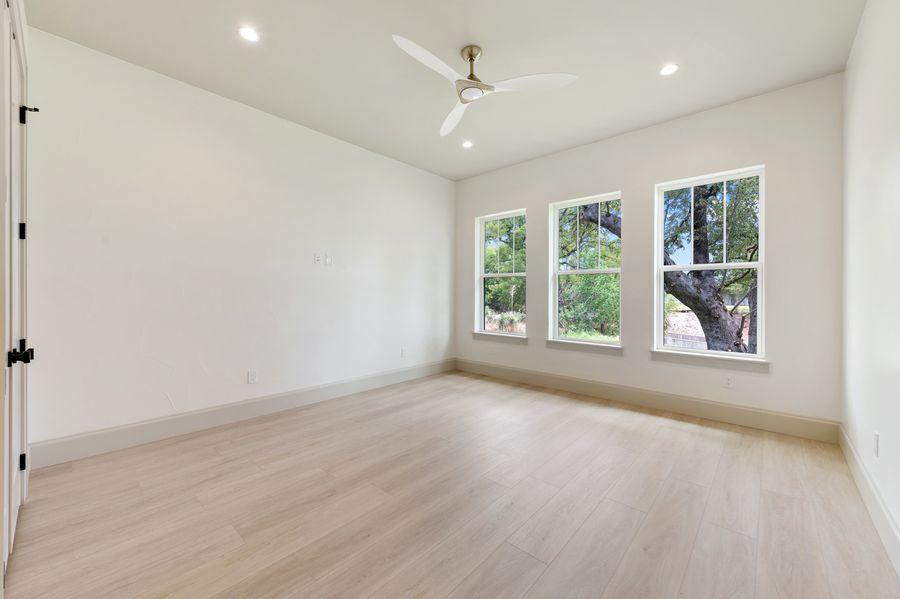 Bedroom with three arched windows looking onto a Texas live oak