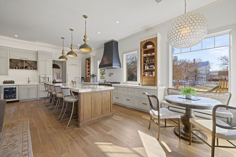 Wide view of the kitchen with hood, brass pendants, and breakfast nook beyond