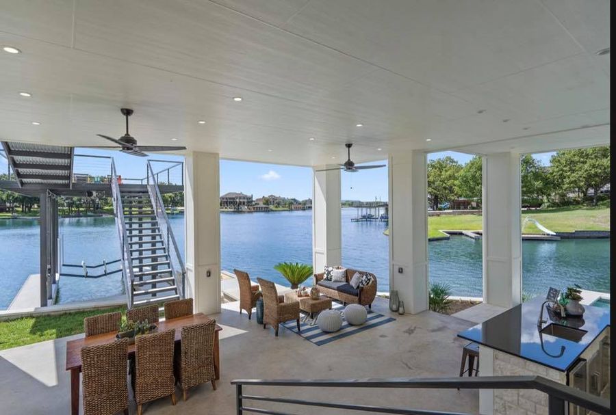 Wide outdoor living room with deep eaves and a long stone fireplace