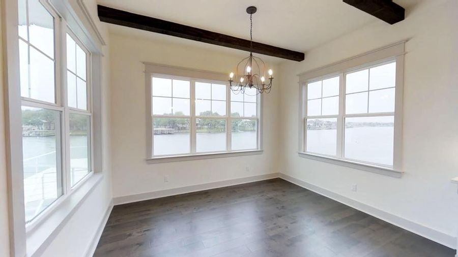 Lakefront dining room with exposed wood beams and iron chandelier